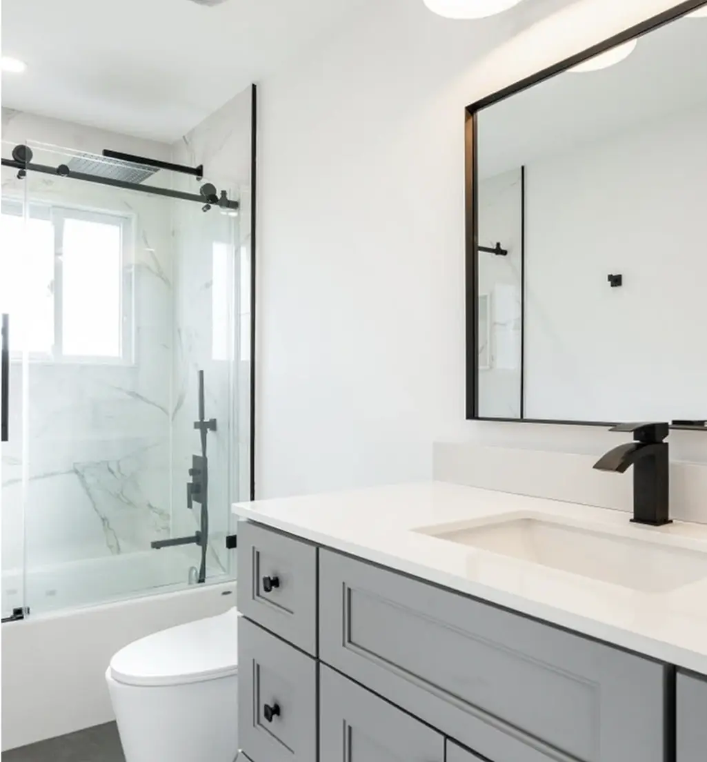 Renovated bathroom with a glass shower and black framed mirror near Milton