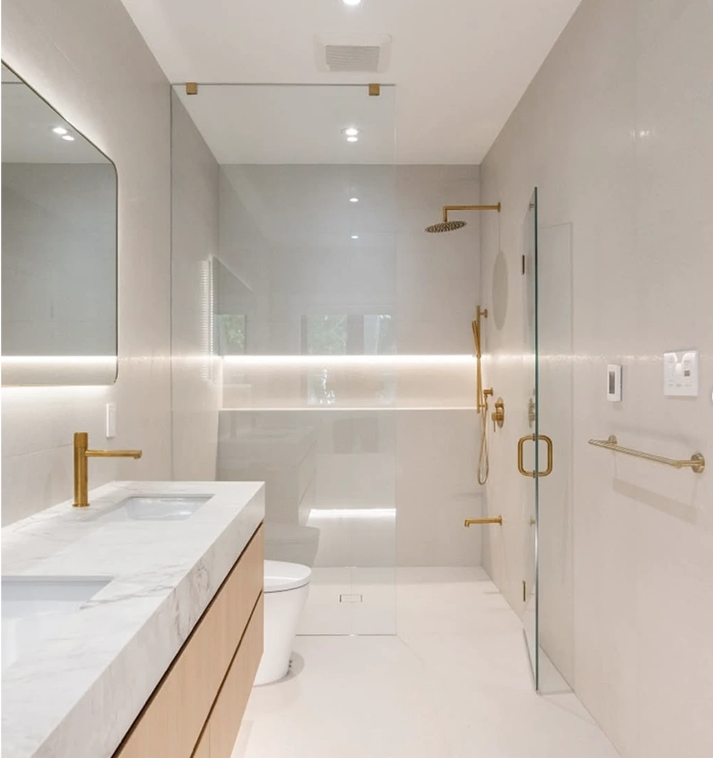 Luxurious bathroom with double vanity, gold fixtures, and glass-enclosed walk-in shower