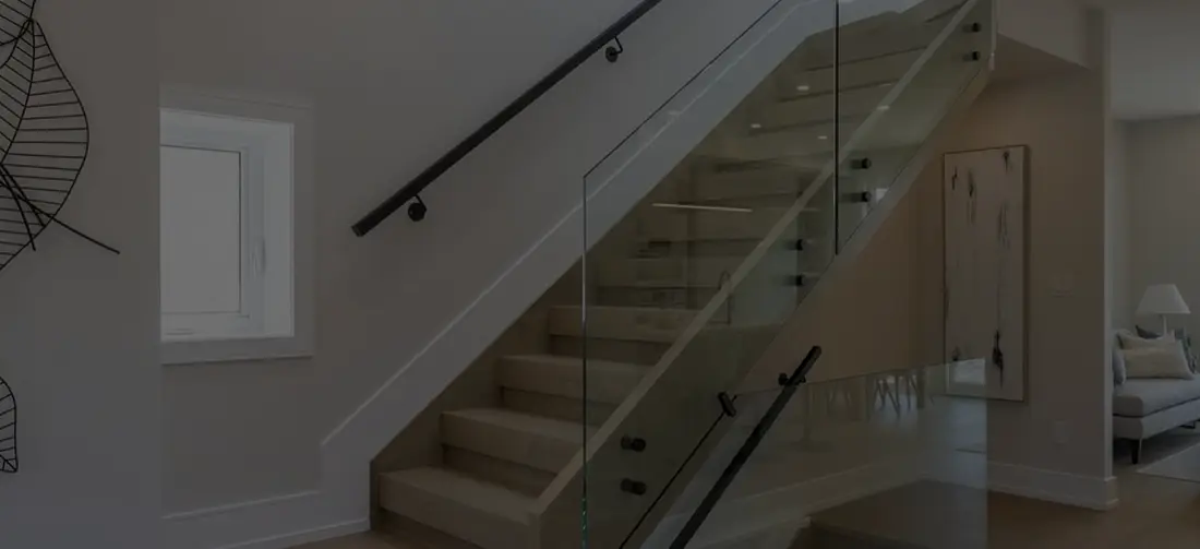 Basement staircase with a glass guard and wall-mounted handrail