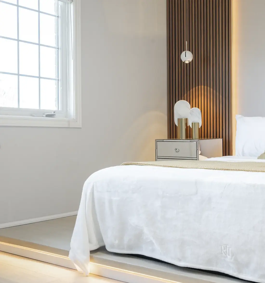 Bedroom with a wood slat feature wall and white bedding near Milton