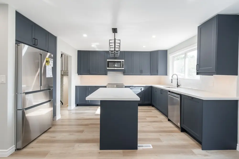 Navy blue kitchen with a large island and stainless steel appliances in a Milton home