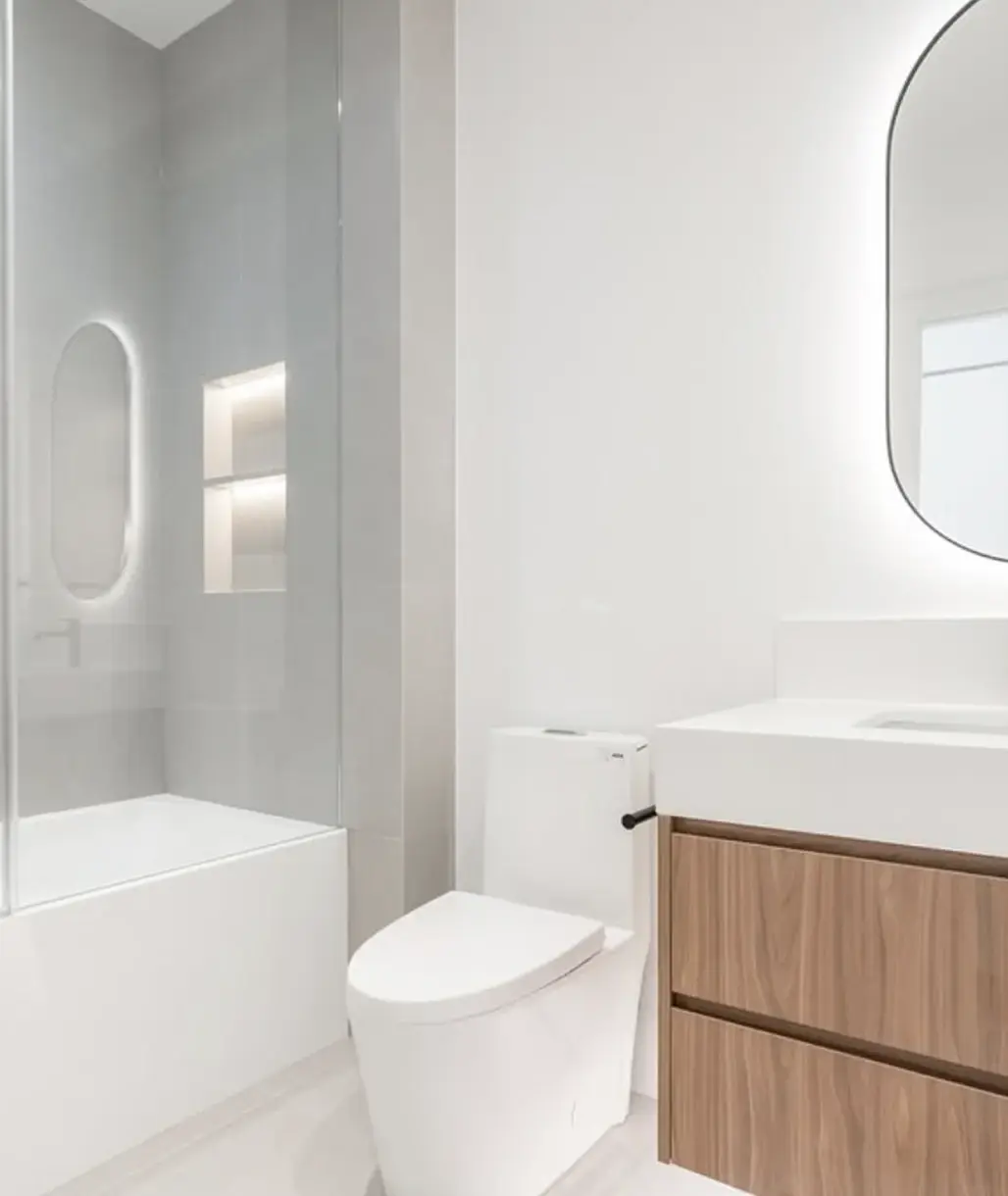 Bathroom with a wood vanity, round mirror and soaker tub near Innisfil