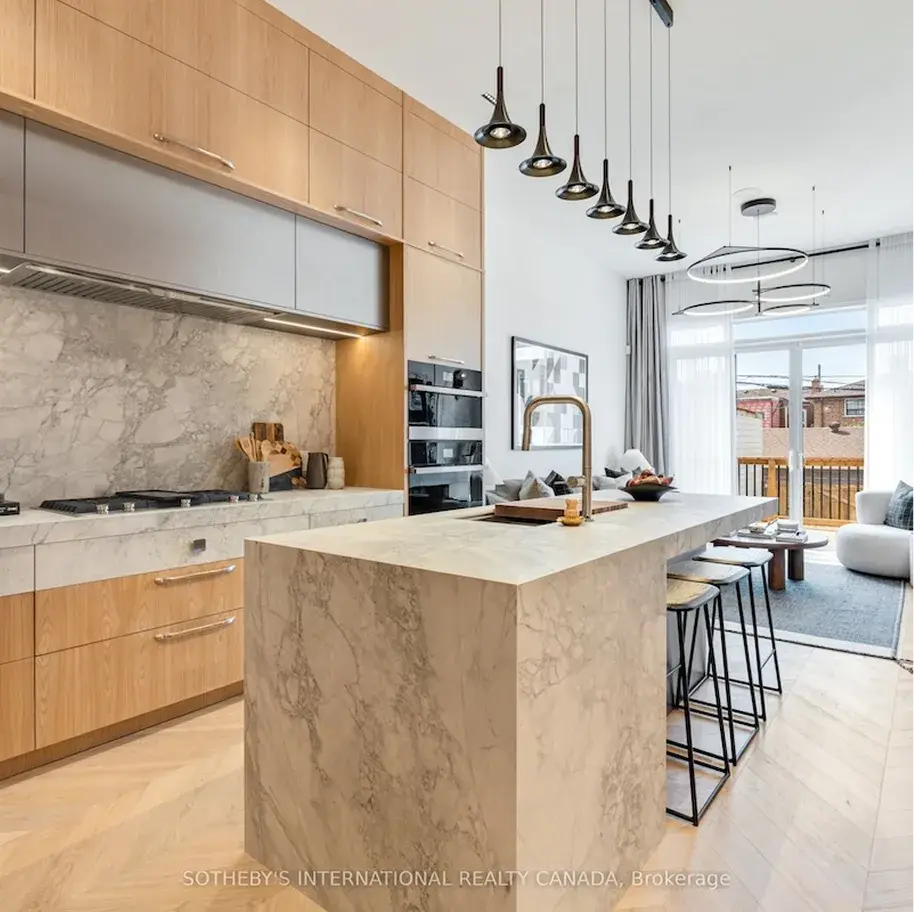 Kitchen with oak cabinetry, a stone island and pendant lighting