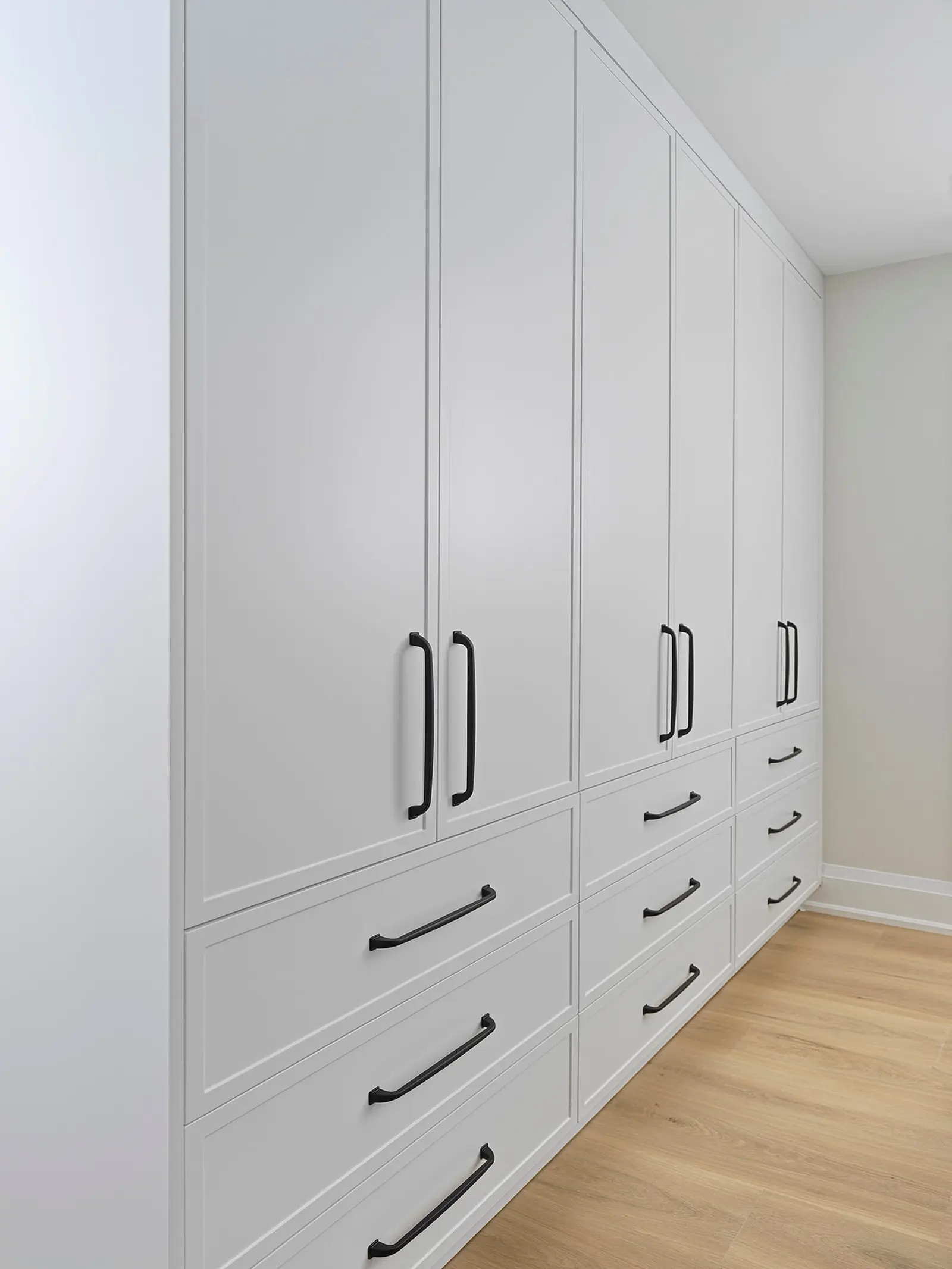 Floor-to-ceiling white pantry cabinets with black hardware