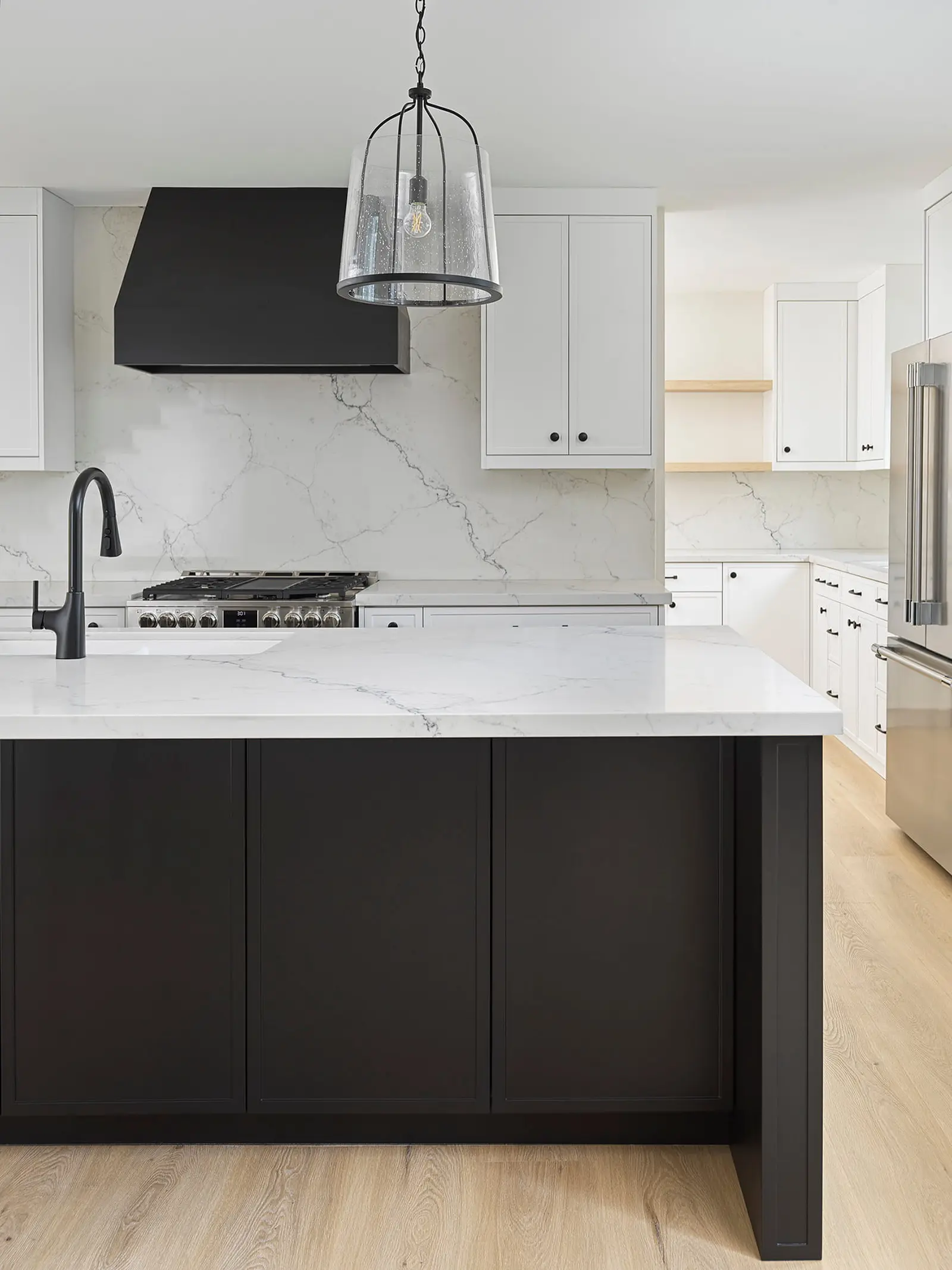 Quartz counter and black island beside a professional gas range