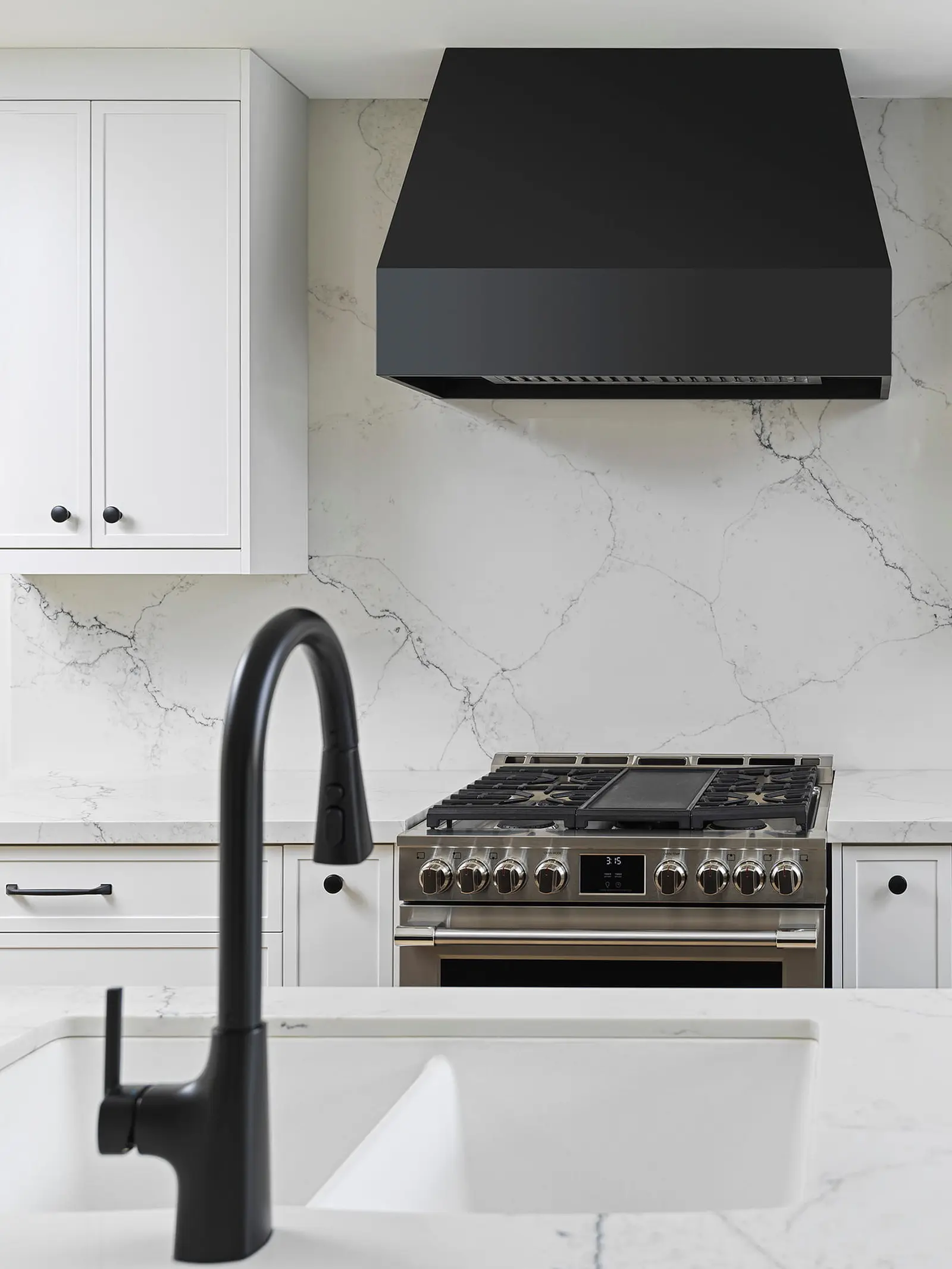 Gas range with a black range hood and marble-look backsplash