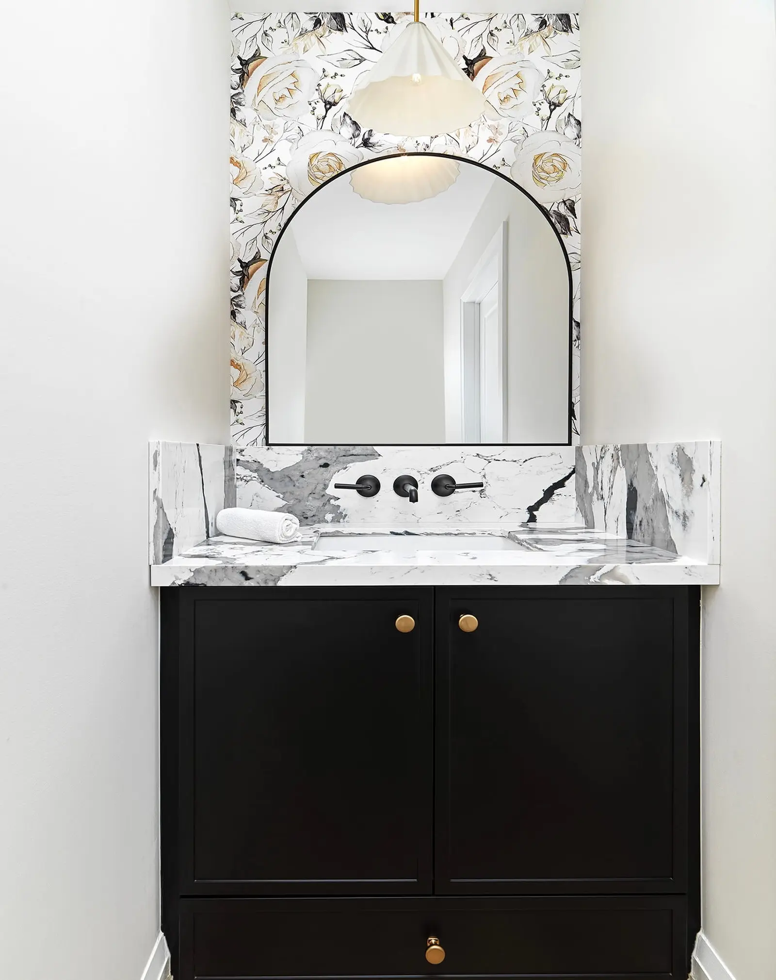 Black vanity with a marble counter and wall-mounted faucet