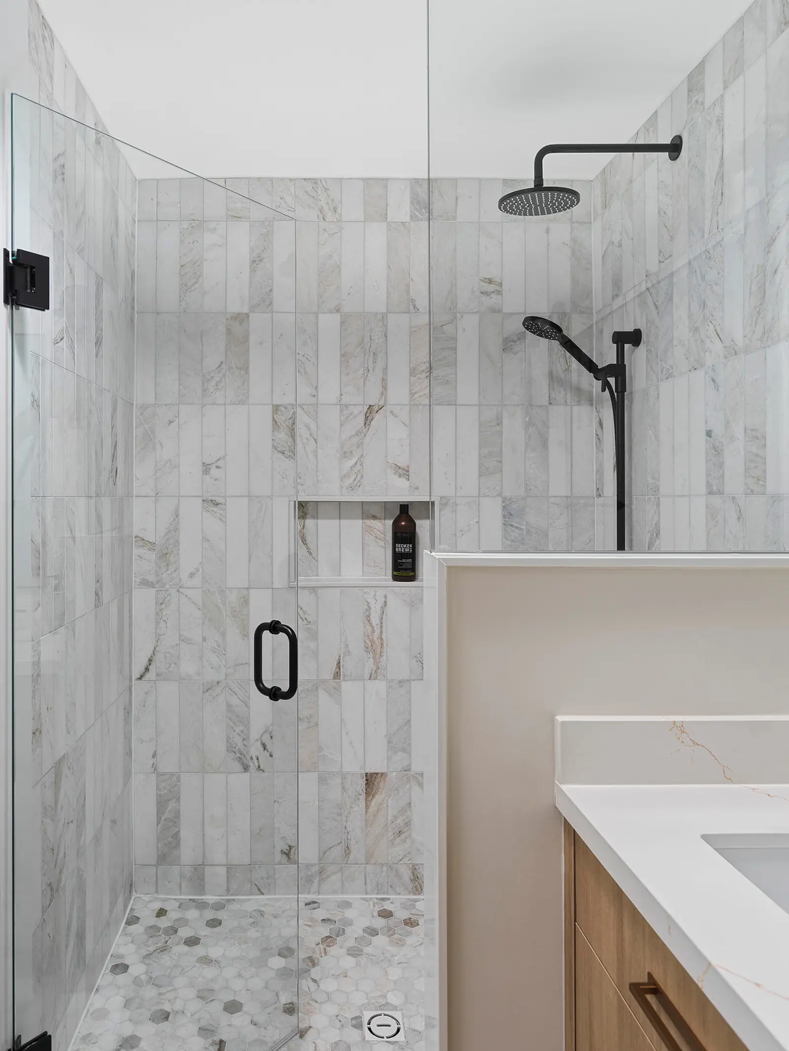 Marble-look tiled shower with a niche and black fixtures