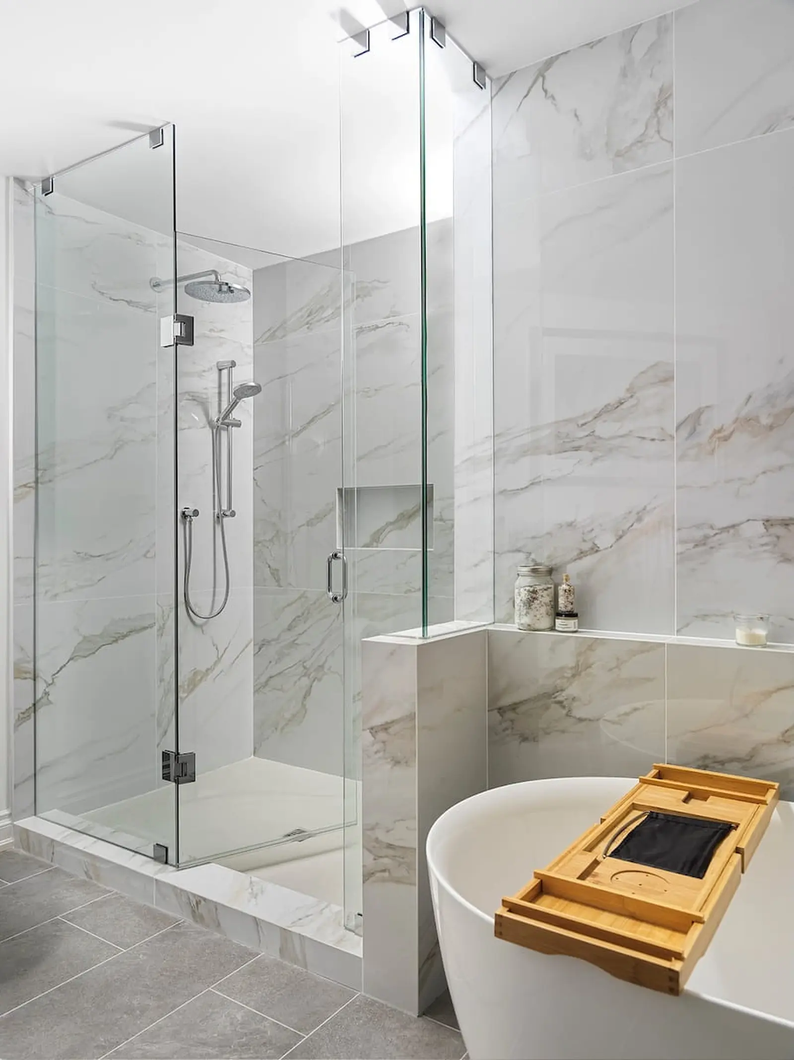 Walk-in glass shower with marble-look tile and a built-in bench