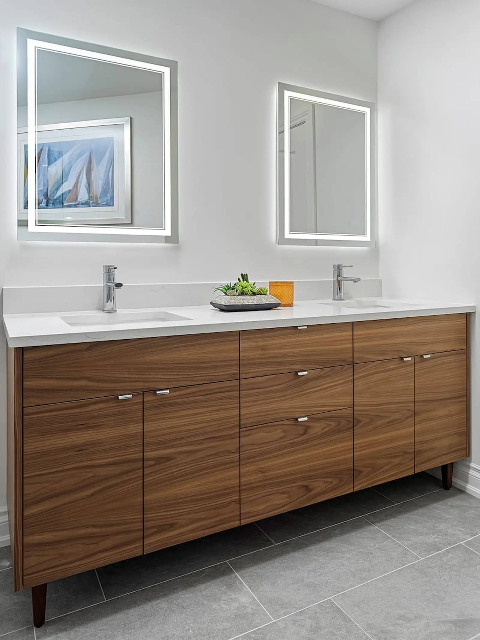 Wood double vanity with a quartz counter and lit mirrors