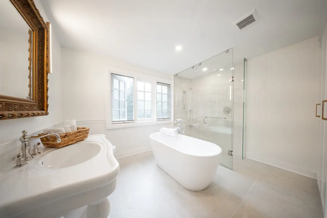 Bright bathroom with a console sink, freestanding tub and glass shower