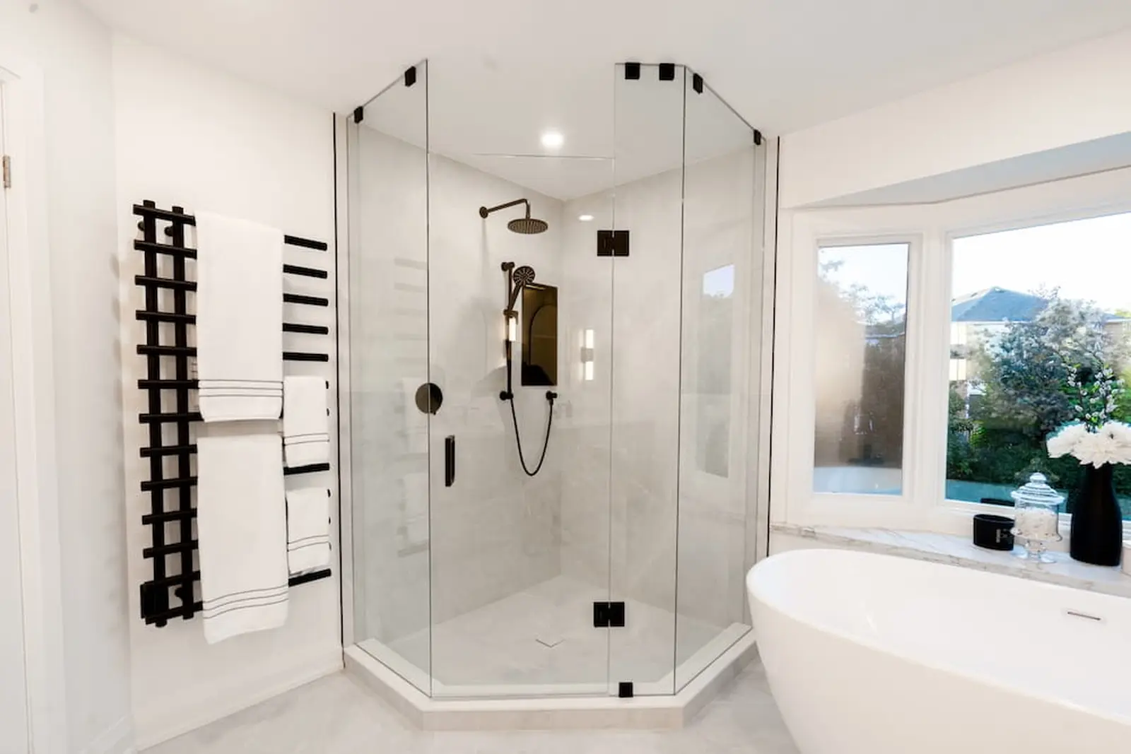 Ensuite with a neo-angle glass shower, black fixtures and a freestanding tub