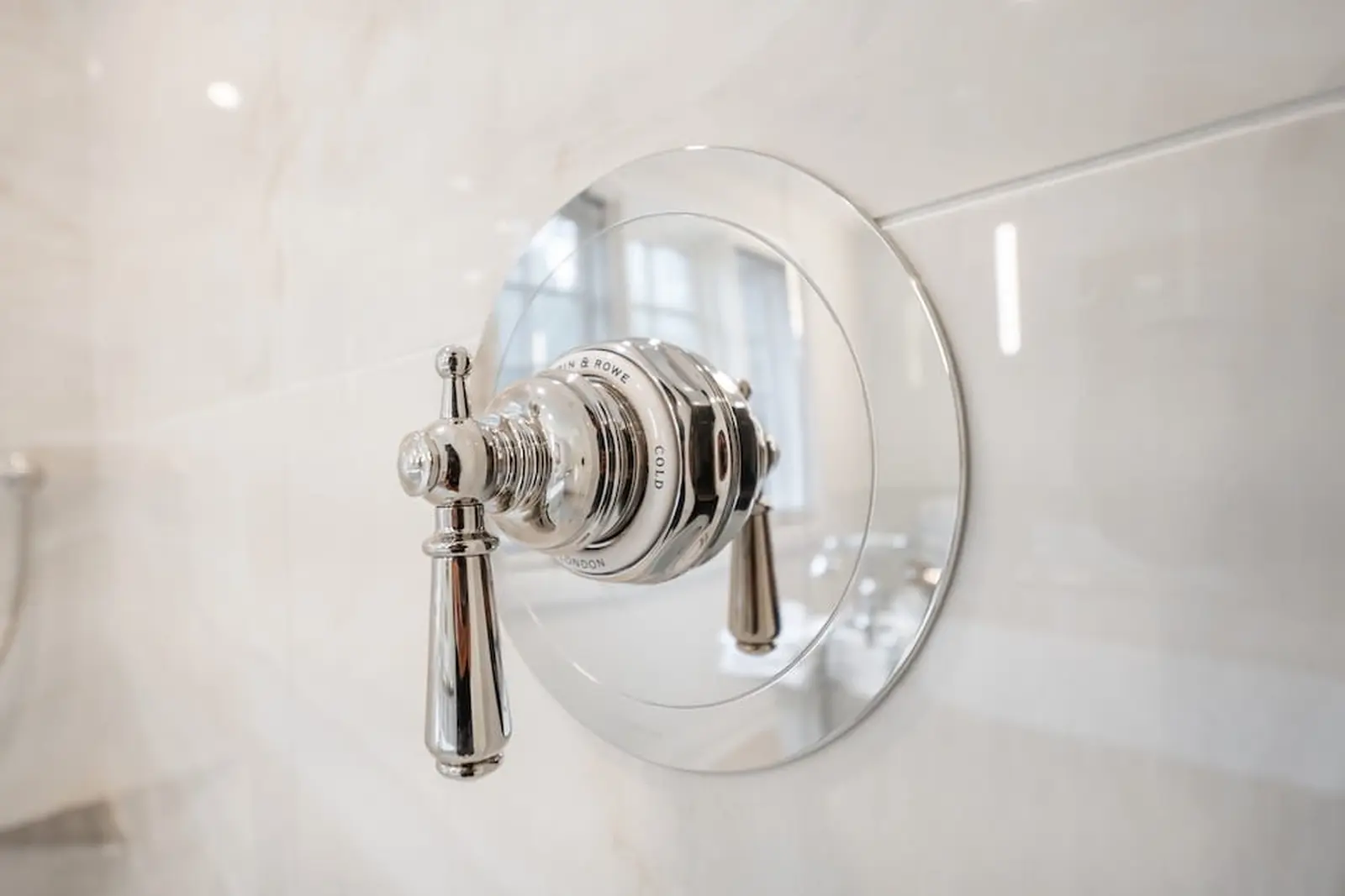 Polished nickel shower valve on marble-look tile