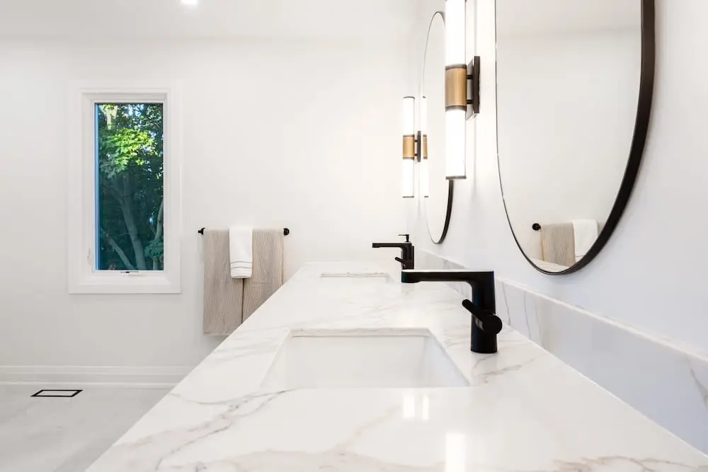 Bathroom vanity with a marble counter and oval mirror in Toronto