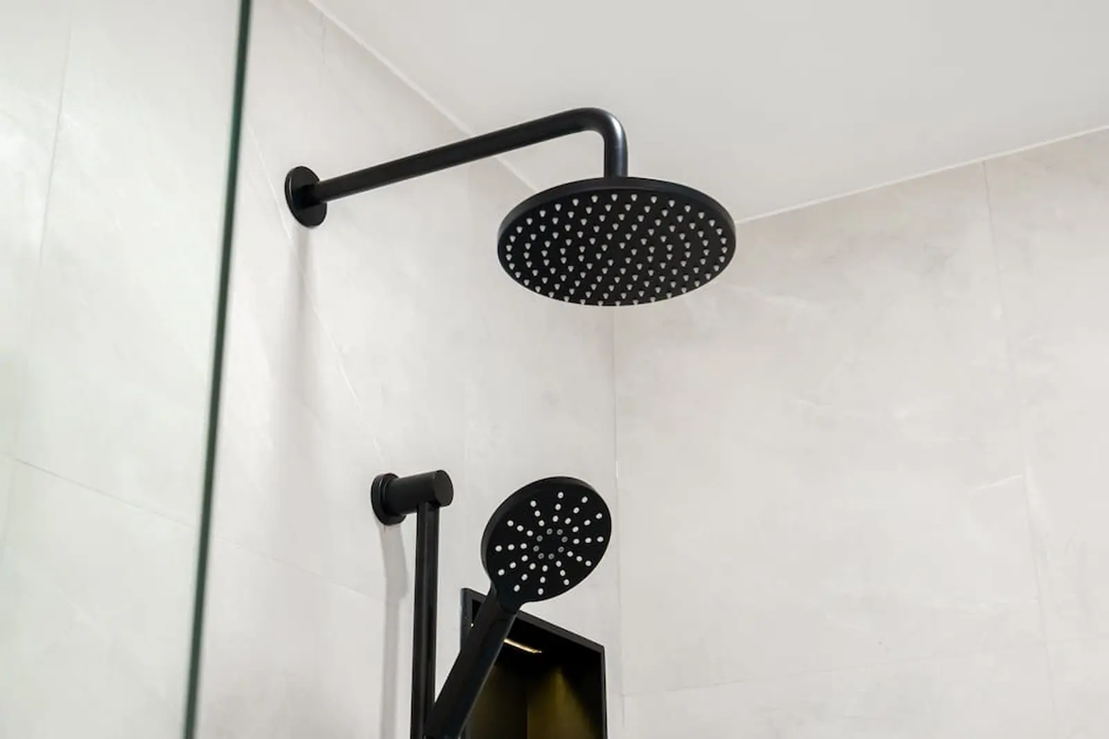 Black rain shower head and hand shower on porcelain tile