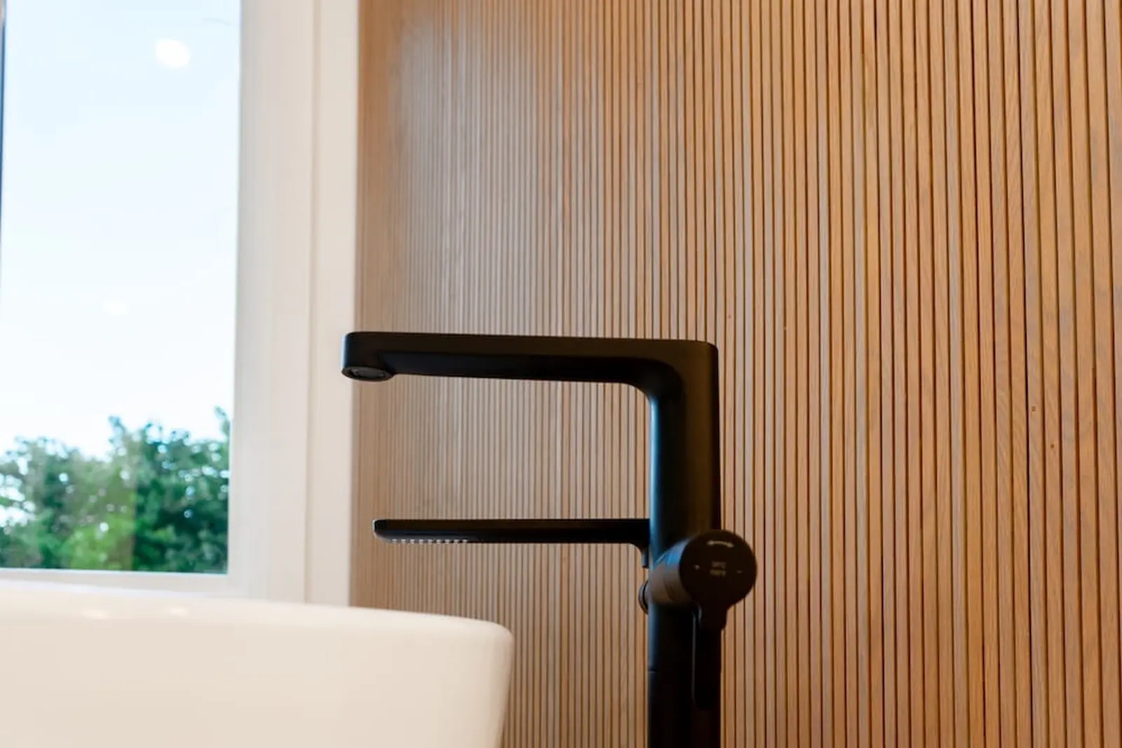 Black faucet against a wood slat feature wall