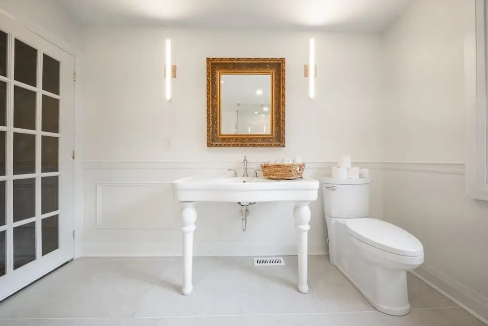 Bright white bathroom with wainscoting and a pedestal sink in Toronto