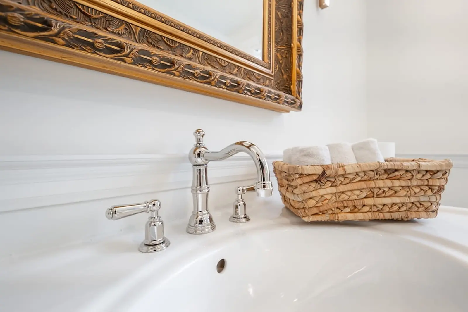 Polished nickel faucet on a white sink with a woven basket