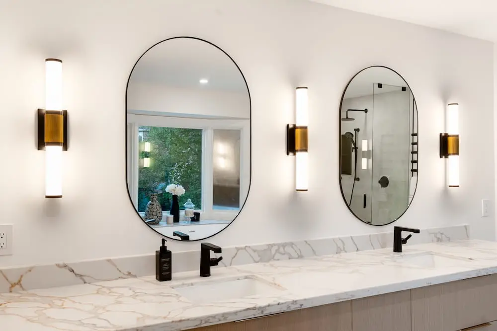 Double vanity with oval mirrors and marble counter near Guelph