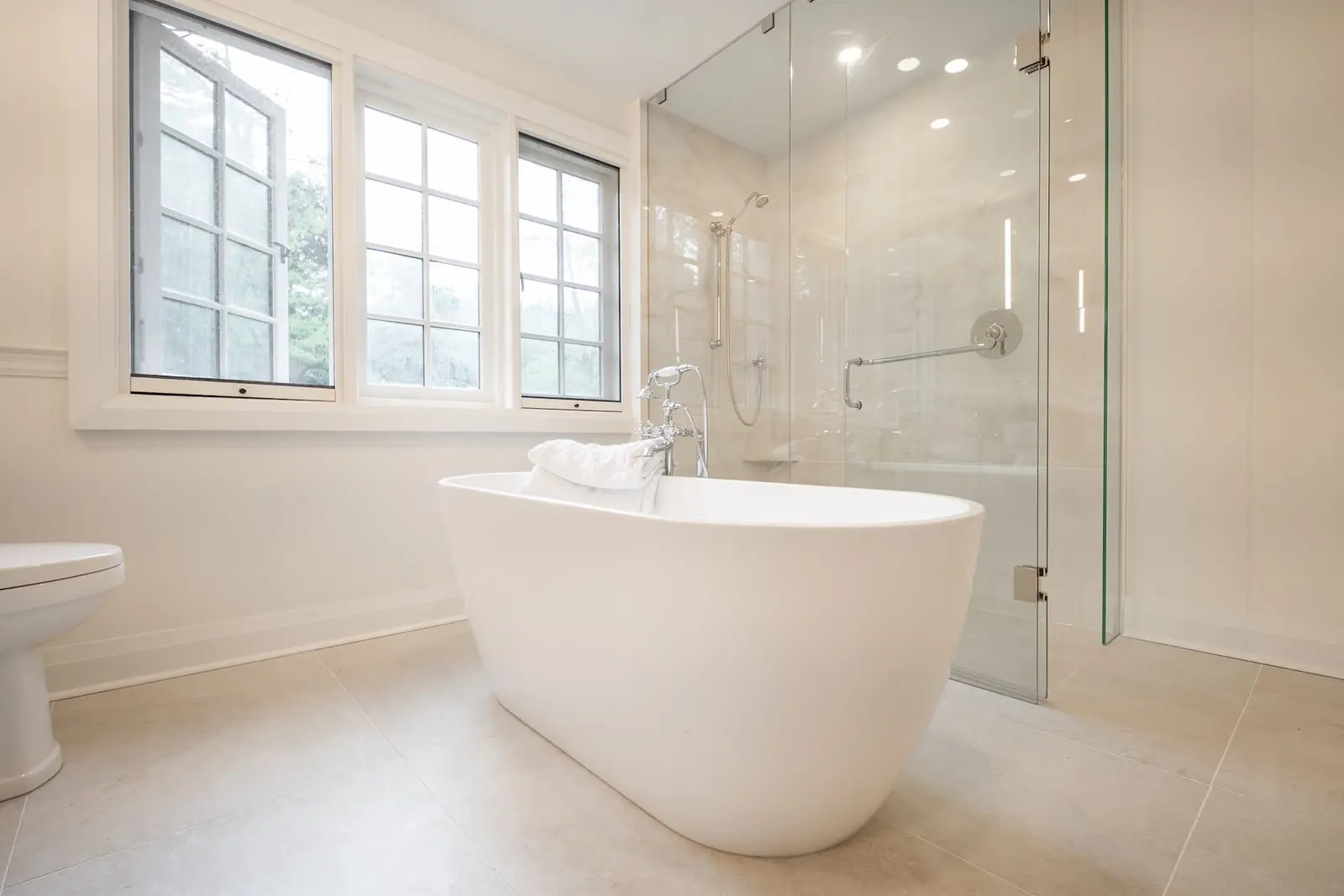 Freestanding tub and glass shower in a white bathroom