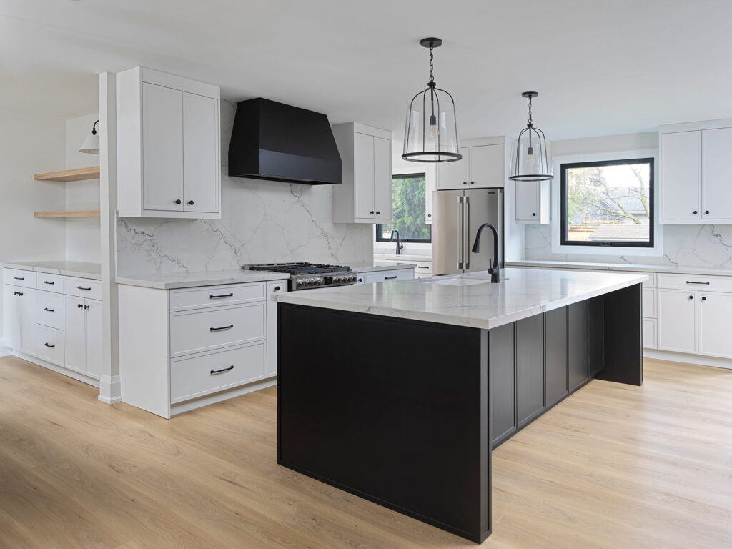 18706 Renovated kitchen with a dark island, white cabinetry and pendant lighting