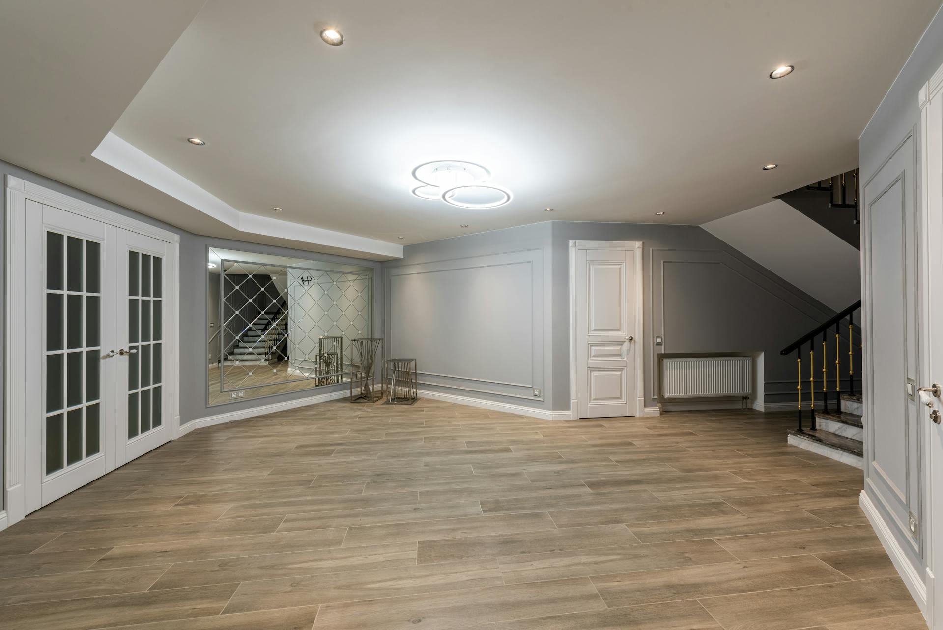 Finished basement recreation room with light flooring and pot lights