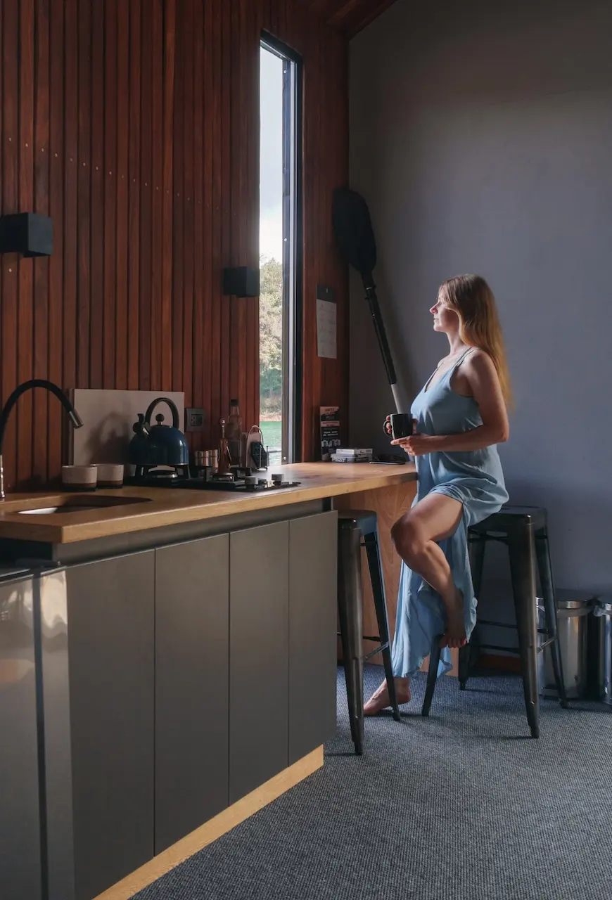 Compact kitchen with a wood slat wall and bar seating inside a backyard suite