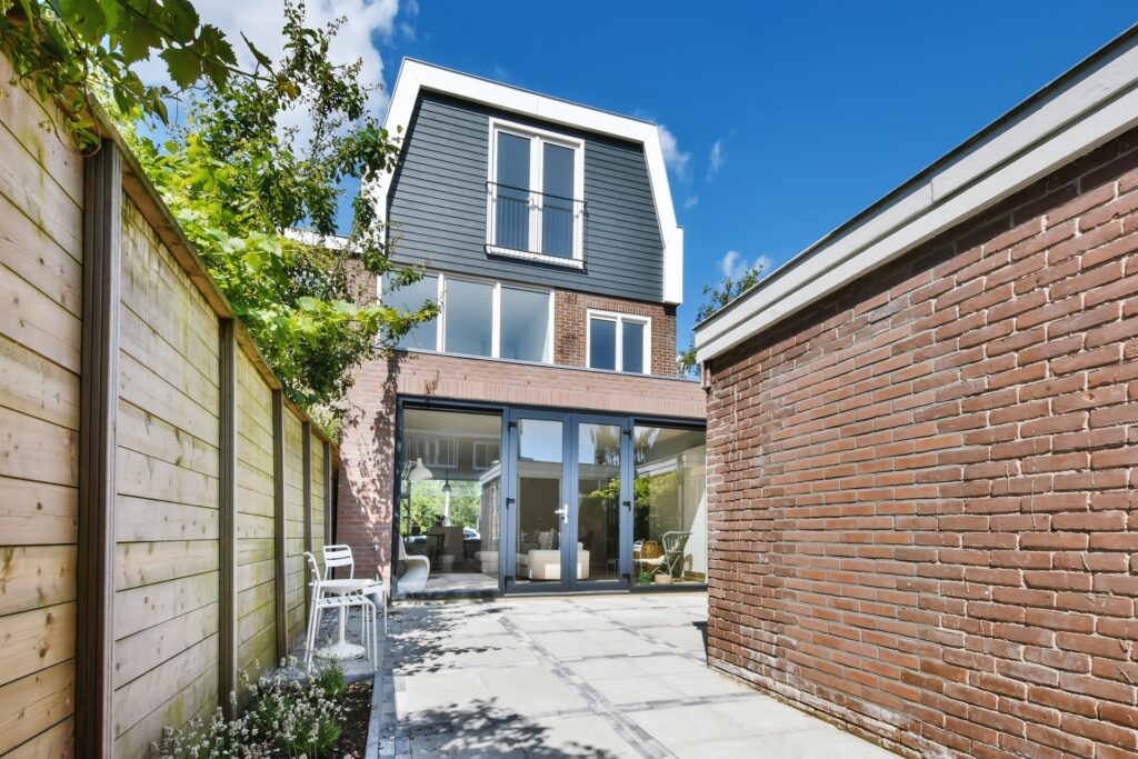 Narrow-lot backyard home with glass doors opening onto a paved patio