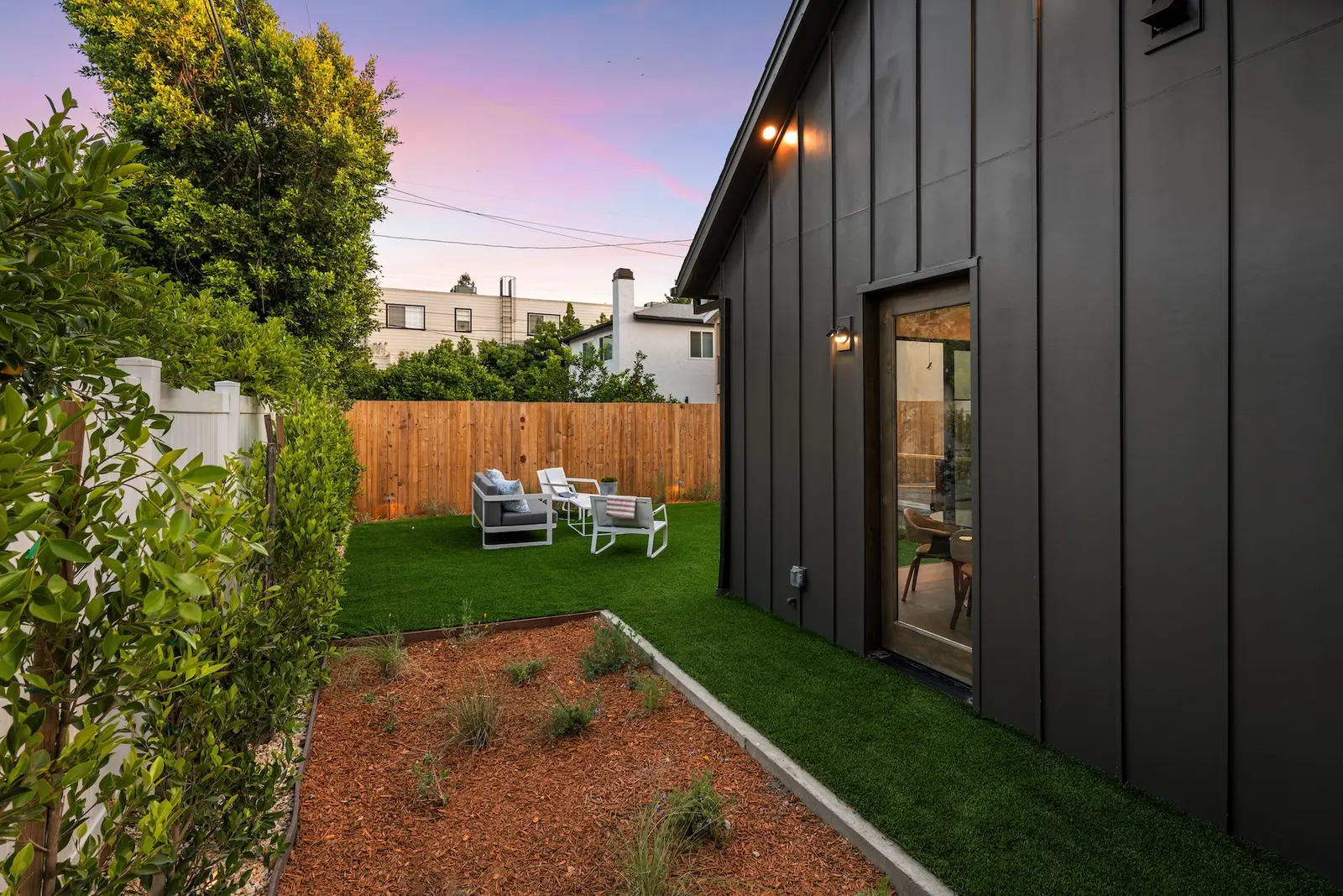 Side path beside a dark board-and-batten backyard suite at dusk