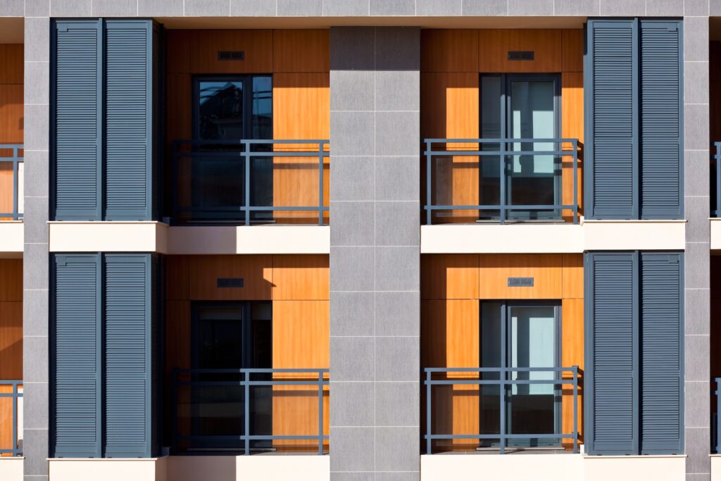 Multiplex building balconies Multi-unit residential facade with stacked balconies and shutters
